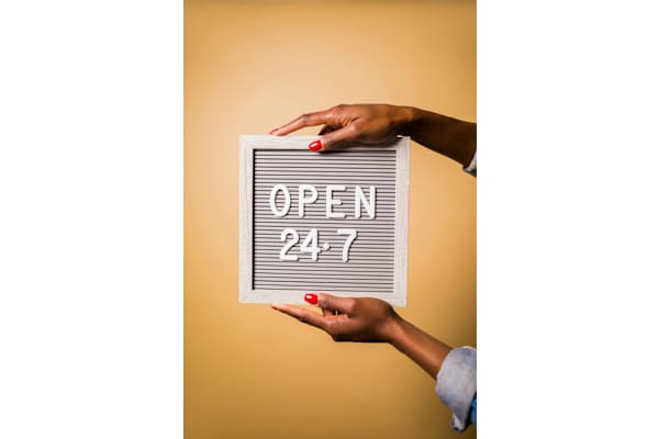 A person holding a sign that says "OPEN 24/7".